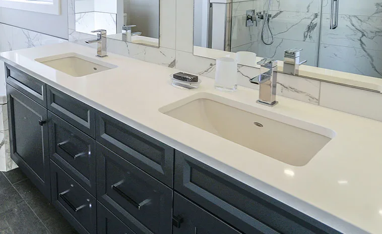 White solid surface bathroom vanity top with double undermount sinks and dark cabinetry